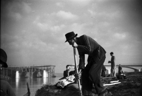 Italia Dopoguerra. Roma. Ponte sul Tevere in costruzione. Operaio al lavoro lungo le sponde del fiume. Sullo sfondo il ponte in costruzione