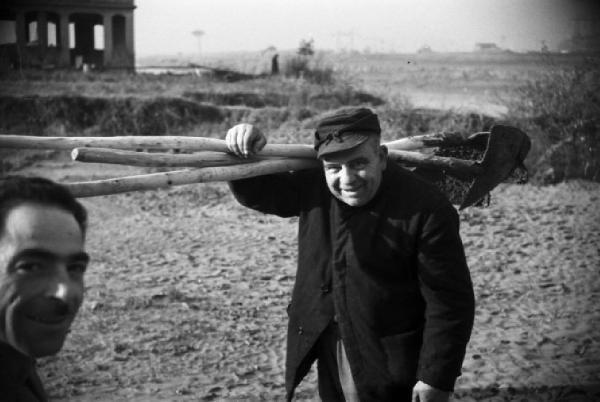 Italia Dopoguerra. Roma. Ponte sul Tevere in costruzione. Ritratto maschile, operaio con vanghe in spalla