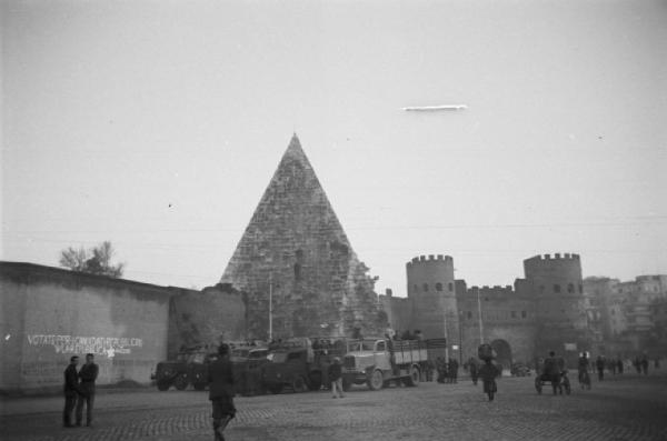 Italia Dopoguerra. Roma. Camionette militari parcheggiate davanti alla piramide di Caio Cestio e Porta San Paolo