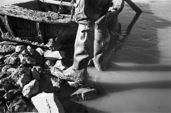 Italia Dopoguerra. Roma. Ponte sul Tevere in costruzione. Opere di consolidamento lungo le sponde del fiume. Operaio che calza stivaloni di gomma