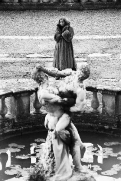 Fotomodella indossa una pelliccia di volpe filettata - cappotto - In primo piano fontana di un giardino storico con gruppo scultoreo "Ercole e Caco"