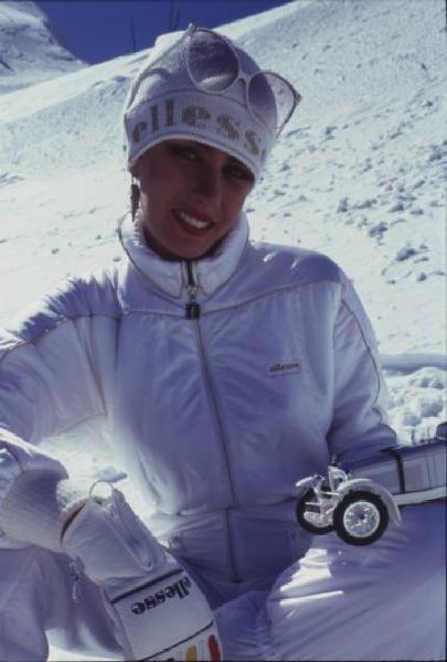 Campagna pubblicitaria Ellesse. Fotomodella indossa tuta da sci bianca - cappello - neve