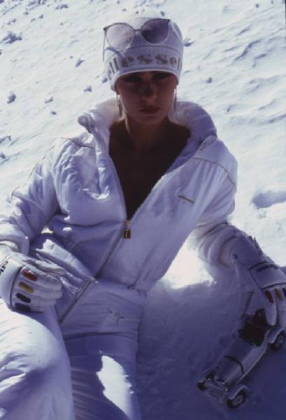 Campagna pubblicitaria Ellesse. Fotomodella indossa tuta da sci bianca - cappello - neve