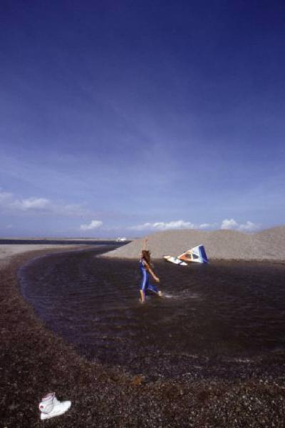 Campagna pubblicitaria Ellesse. Fotomodella indossa una muta - torrente - scarpa da ginnastica - windsurf