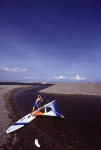 Campagna pubblicitaria Ellesse. Fotomodella indossa una muta - torrente - scarpa da ginnastica - windsurf