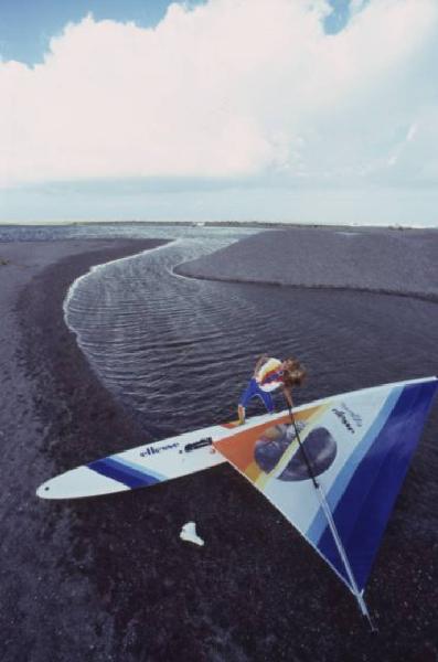 Campagna pubblicitaria Ellesse. Fotomodella indossa una muta - torrente - scarpa da ginnastica - windsurf