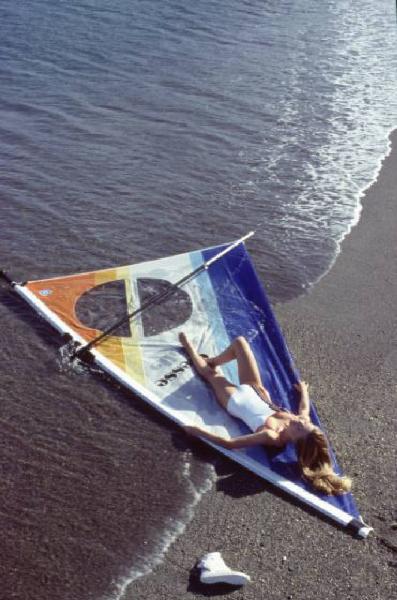 Campagna pubblicitaria Ellesse. Fotomodella indossa costume da bagno intero bianco -  vela di un windsurf