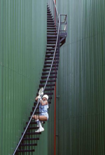 Campagna pubblicitaria Ellesse. Fotomodella indossa completo da tennis - scala e ringhiera di un gasometro