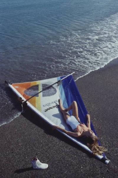 Campagna pubblicitaria Ellesse. Fotomodella indossa costume da bagno intero bianco - vela di un windsurf