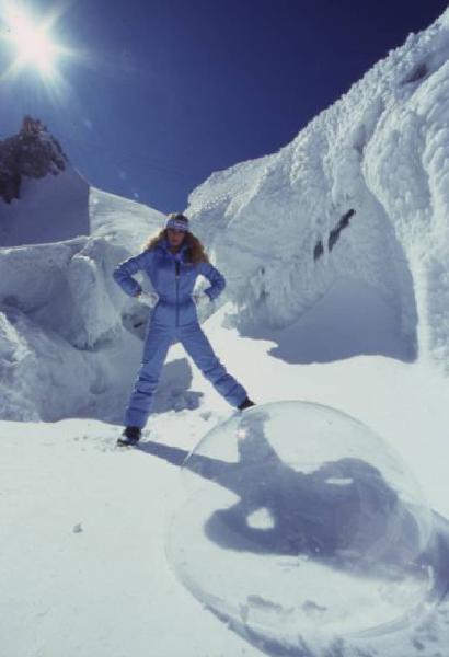 Campagna pubblicitaria Ellesse. Fotomodella indossa completo da sci azzurro - neve - sfera di plexiglass