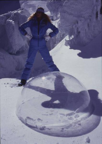 Modella sulla neve con sfera di plastica trasparente