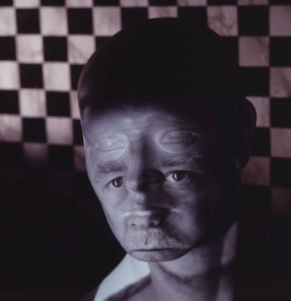 Klaustrofobia. Ritratto maschile - autoritratto dell'artista "Maschera pelata" su fondale a scacchiera