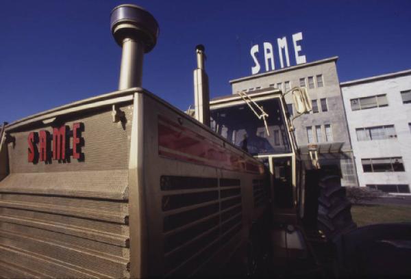 Gruppo SAME, stabilimento di Treviglio. Trattore agricolo - ripresa di scorcio; ingresso dello stabilimento sullo sfondo