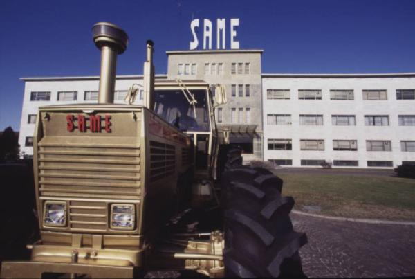 Gruppo SAME, stabilimento di Treviglio. Trattore agricolo in primo piano; ingresso dello stabilimento sullo sfondo