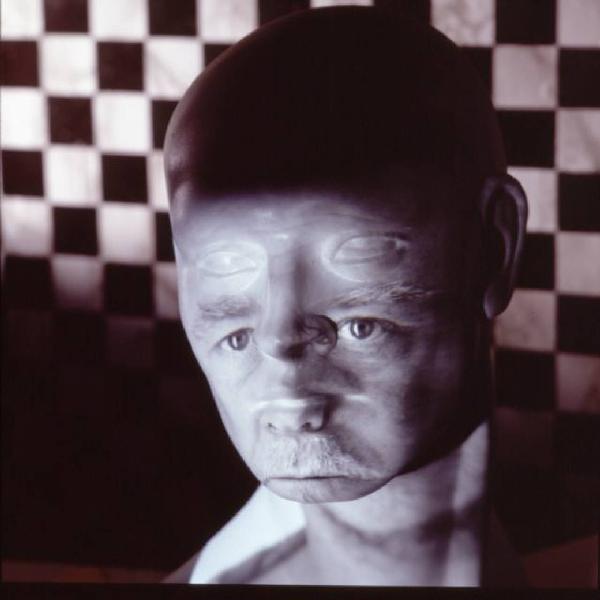 Klaustrofobia. Ritratto maschile - autoritratto dell'artista "Maschera Pelata" proiettato su fondale a scacchiera