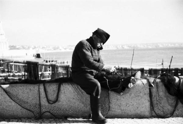 Cascais. Pescatore aggiusta le reti seduto su un muretto