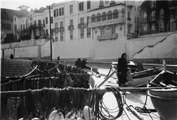 Cascais. Reti da pesca stese ad asciugare e imbarcazioni in secca. Sullo sfondo alcuni edifici affacciati sul porticciolo