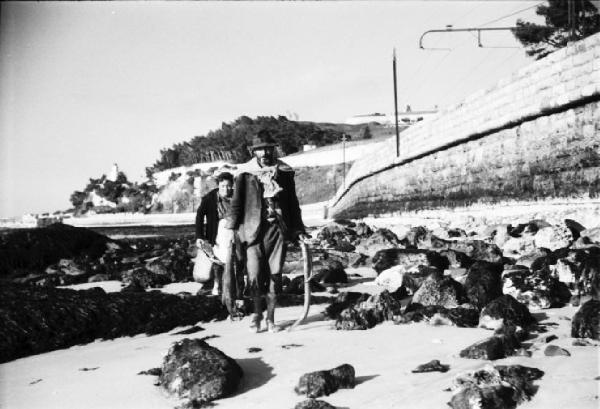 Cascais. Spiaggia con la bassa marea - abitanti del paese alla ricerca di molluschi. A lato la massicciata della ferrovia