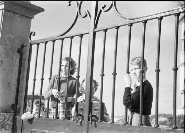 Estoril. Famiglia Savoia in esilio. Maria Pia, Maria Beatrice, Maria Gabriella e Vittorio Emanuele IV in giardino - guardano attraverso le sbarre del cancello