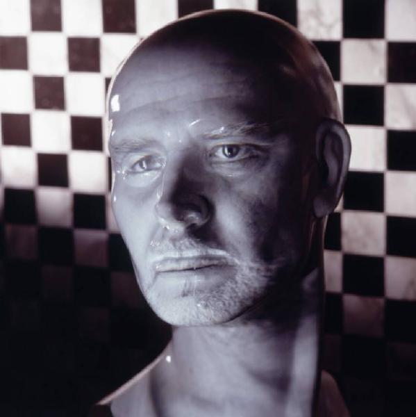 Klaustrofobia. Ritratto maschile - autoritratto dell'artista "Maschera pelata" su fondale a scacchiera