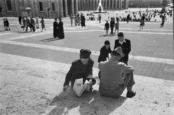 Città del Vaticano. Piazza San Pietro. Militare statunitense e ragazza che legge un quotidiano americano seduti sulla gradinata - sullo sfondo il sagrato