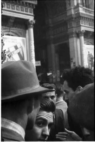 Milano. Piazza Duomo. Gente che discute davanti all'ingresso di Galleria Vittorio Emanuele II - sullo sfondo due manifesti elettorali della Democrazia Cristiana