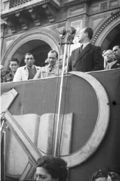 Milano. Piazza Duomo. Politico parla dal palco dei comizi - a lato i compagni di partito - sul fronte del palco lo stemma della falce e martello