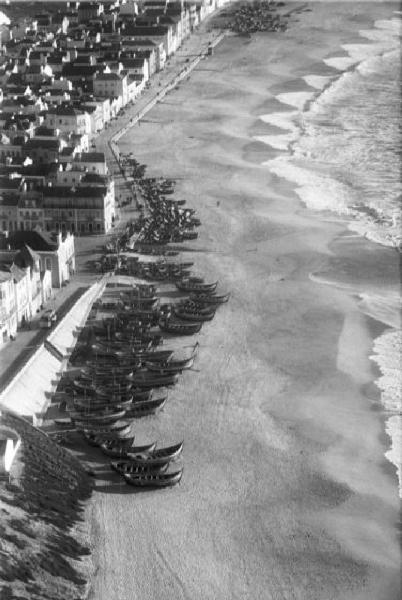 Nazaré. Le case del paese che si affacciano sulla spiaggia - imbarcazioni da pesca in secca e onde che frangono