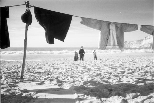 Nazaré - bambini in spiaggia. In primo piano panni stesi ad asciugare