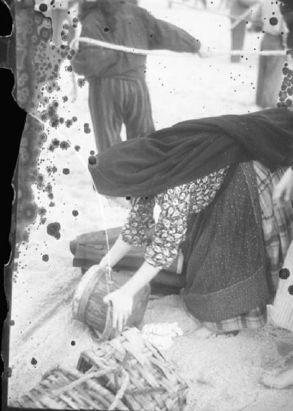 Spiaggia di Nazaré - donna raccoglie un secchio di legno