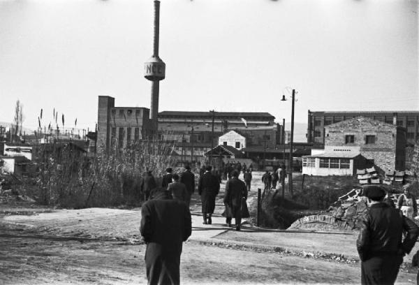 Barcellona - operai si dirigono in fabbrica. L'impianto industriale sullo sfondo