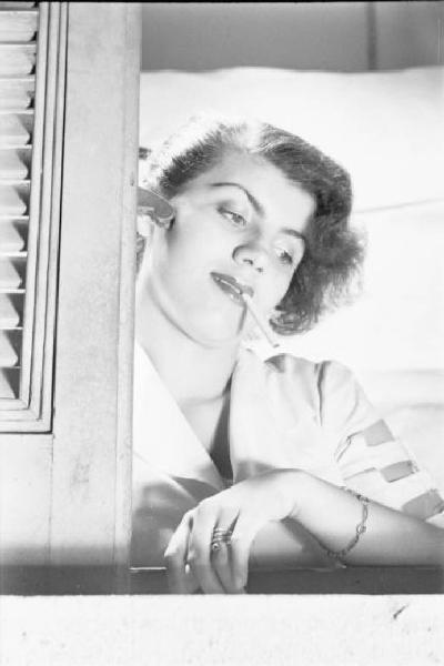 Milano - giovane donna alla finestra. Sigaretta in bocca