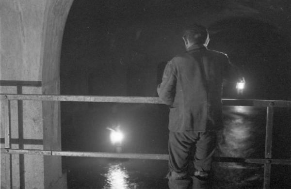 Milano - lavori di manutenzione delle fognature. Operaio in galleria osserva le acque alla luce delle torce