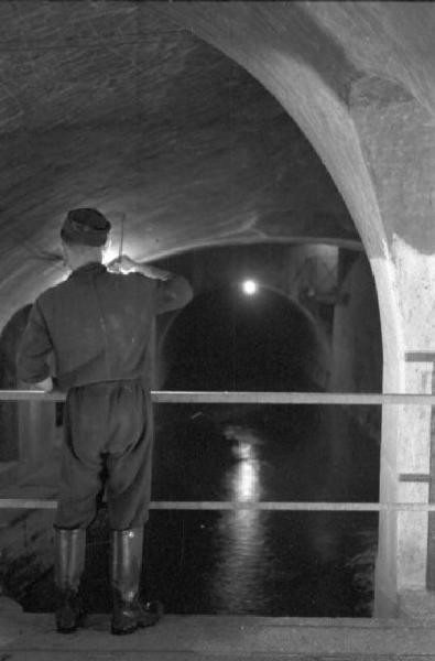 Milano - lavori di manutenzione delle fognature. Operaio in galleria osserva le acque alla luce delle torce