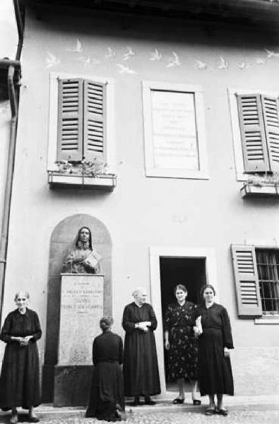 Italia Dopoguerra. Sant'Angelo Lodigiano. Reportage sulla figura di Santa Francesca Cabrini - gruppo di donne del paese in preghiera davanti al monumento della Beata