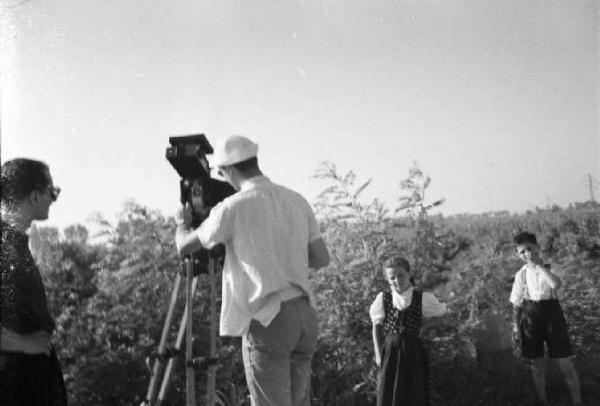 Italia Dopoguerra. Sant'Angelo Lodigiano. Reportage sulla figura di Santa Francesca Cabrini - Federico Patellani in una zona campestre durante le riprese, circondato da alcuni abitanti