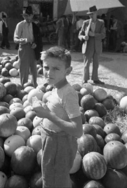 Italia Dopoguerra. Sant'Angelo Lodigiano. Reportage sulla figura di Santa Francesca Cabrini - adolescente in posa a fianco di un cumulo di angurie