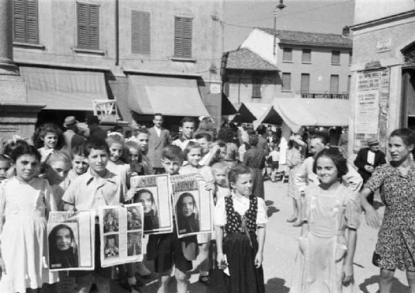 Italia Dopoguerra. Sant'Angelo Lodigiano. Reportage sulla figura di Santa Francesca Cabrini - un gruppo di giovani abitanti mostra la copertina del settimanale "La domenica" che ritrae la fotografia della Beata