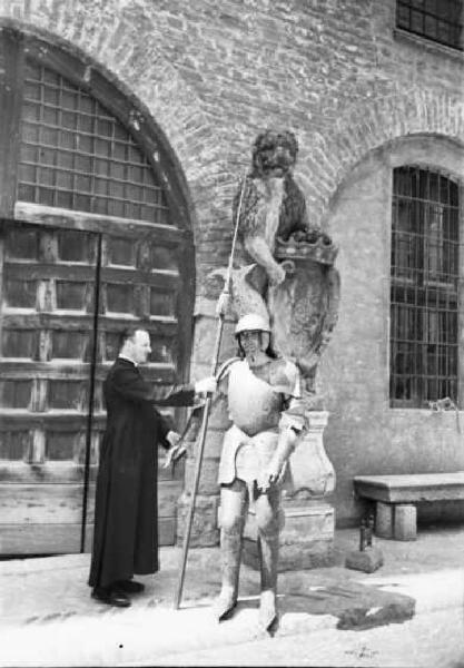 Italia Dopoguerra. Sant'Angelo Lodigiano. Reportage sulla figura di Santa Francesca Cabrini - il parroco mentre gioca con una armatura in una via del paese