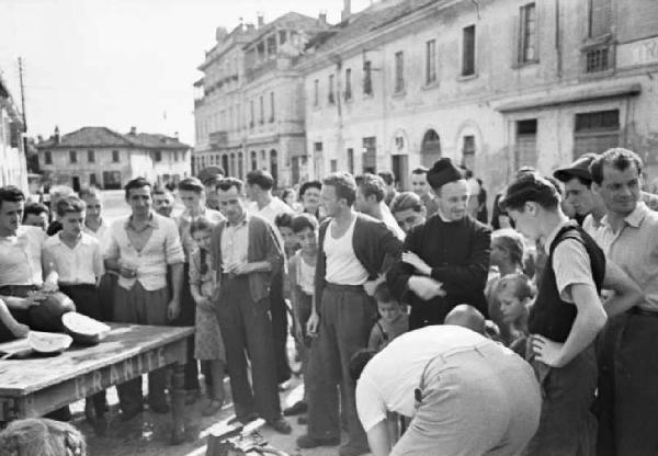 Italia Dopoguerra. Sant'Angelo Lodigiano. Reportage sulla figura di Santa Francesca Cabrini - il parroco nelle strade del paese circondato dagli abitanti