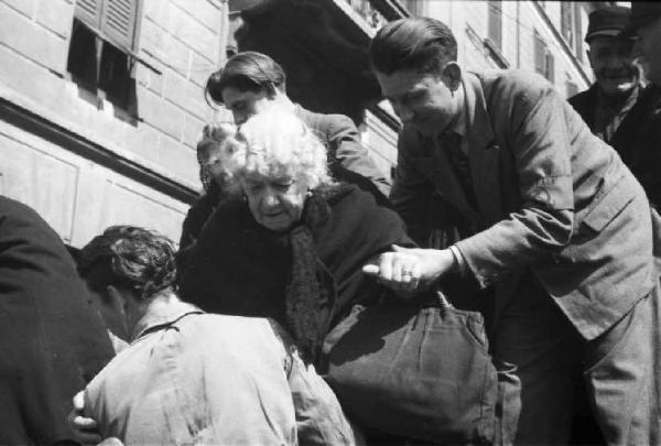 Italia Dopoguerra. Milano. Elezioni amministrative del 1947. Un carro carico di cittadini fermo davanti al seggio elettorale.- un uomo aiuta una anziana signora a scendere da un carro