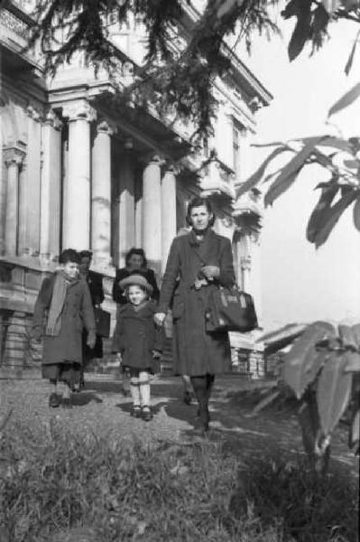 Milano dopoguerra. Signora con bambini all'uscita di un edificio pubblico dopo la visita medica