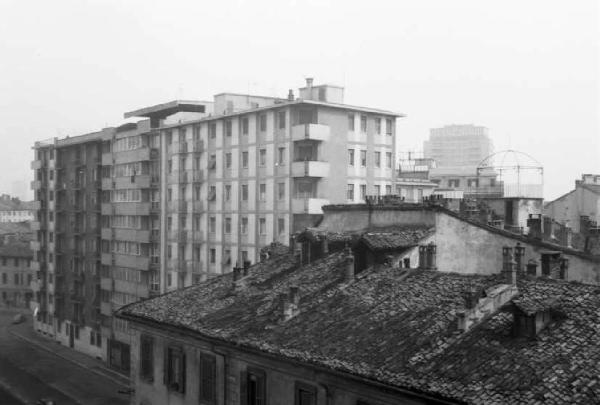 Prove Canon e Summicron. Veduta di Milano da una finestra, con tetto di casa a corte in primo piano e palazzi per abitazioni sullo afondo. Zona Arena/Sempione