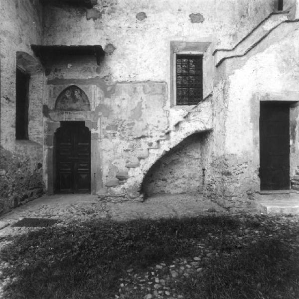 Grosio - Cortile della chiesa di San Giorgio - scala esterna, finestra, due porte, una sovrastata da un affresco