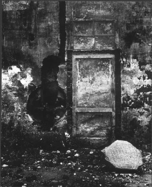 Milano - Muro con porta e finestra scrostato e scavato - in primo piano una grossa pietra abbandonata a terra