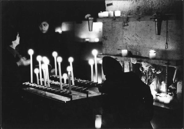 Culto ritualizzato dei morti. Napoli - Cimitero delle Fontanelle, interno - Alcune devote accendono ceri