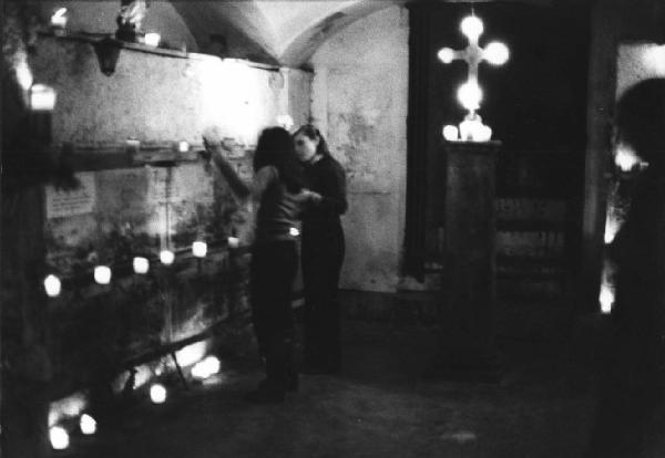 Culto ritualizzato dei morti. Napoli - Cimitero delle Fontanelle, interno - Alcune devote accendono lumini - A lato un crocefisso luminoso