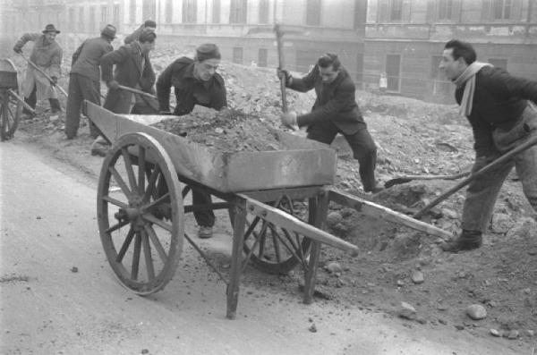 Italia Dopoguerra. Milano - Strada - Macerie - Operai al lavoro con pala - Sgombero macerie - Carro