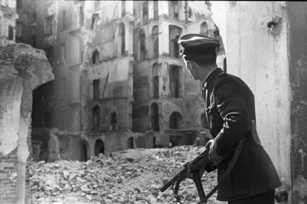 Italia Dopoguerra. Milano - Quartiere distrutto dai bombardamenti - Macerie - Vigile con mitra