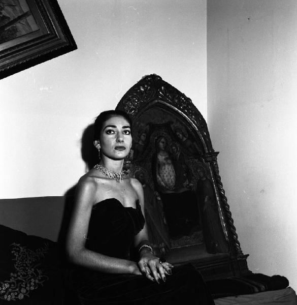 Milano - Abitazione di Maria Callas: interno - Ritratto femminile: Maria Callas (cantante lirica) seduta accanto ad una pala d'altare antica